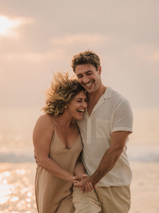 Couple laughing together on the beach at dusk