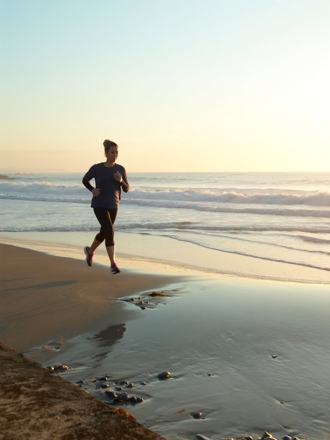 Woman jogging along the shoreline at sunrise